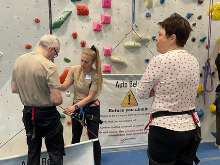 Up Ending Parkinson's Ambassador Sophia helping a climber set up his harness