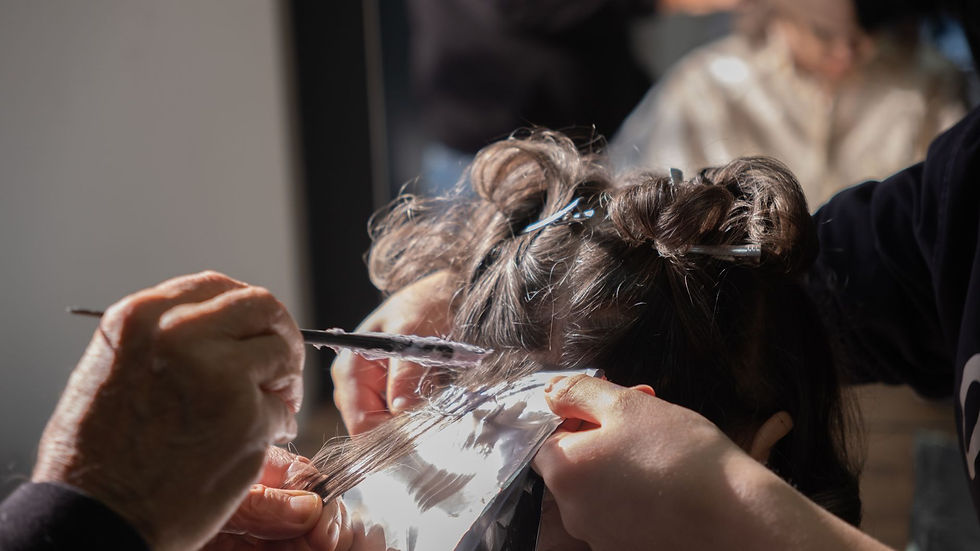Hairdresser applying foil highlights to client's hair in a salon.