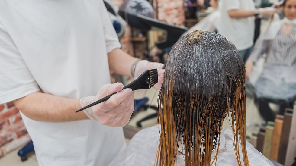 Hair coloring process in a salon, showcasing stylist applying color to client's hair.