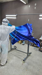 Applying the finish to Wind Panel VI in the spray booth.