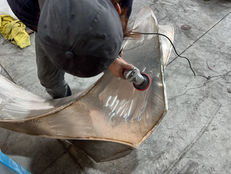 A handheld abrasive tool is used to work the metal surface after joining.