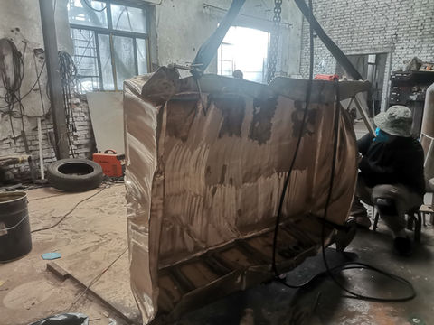 The table is supported upright so the workshop team can reach its broad metal surface.