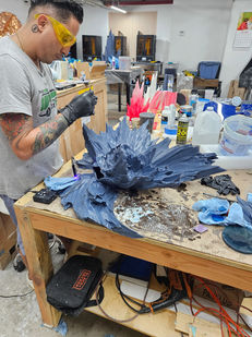 A craftsperson works closely on the resin form at the bench.