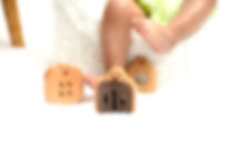 Baby sitting on soft white fur rug playing with wooden baby toys – including a wooden ratt