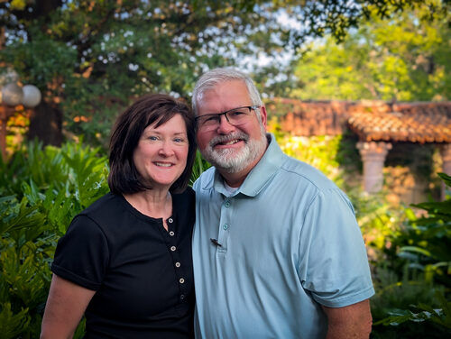 Smiling couple posing outdoors at an event garden.