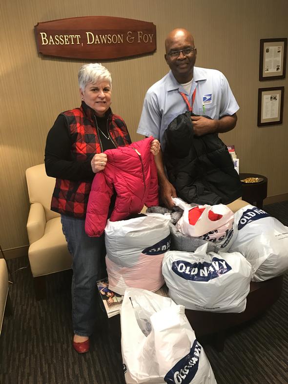 Two people holding winter coats at a charity drive
