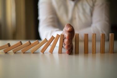 Hand stopping falling wooden blocks in a row.