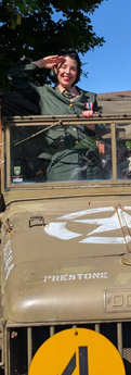Rosie B in military uniform saluting from a vintage jeep