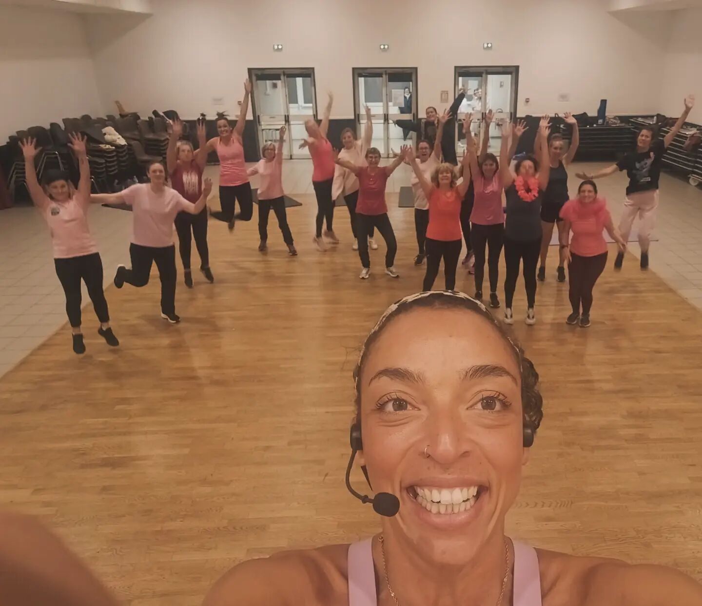 Isabelle, coach Sport Totem, en selfie devant un groupe qui saute bras en l'air dans une grande salle