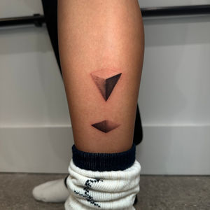 a woman 's leg has a tattoo of geometric triangles on it