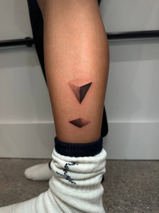 a woman 's leg has a tattoo of geometric triangles on it