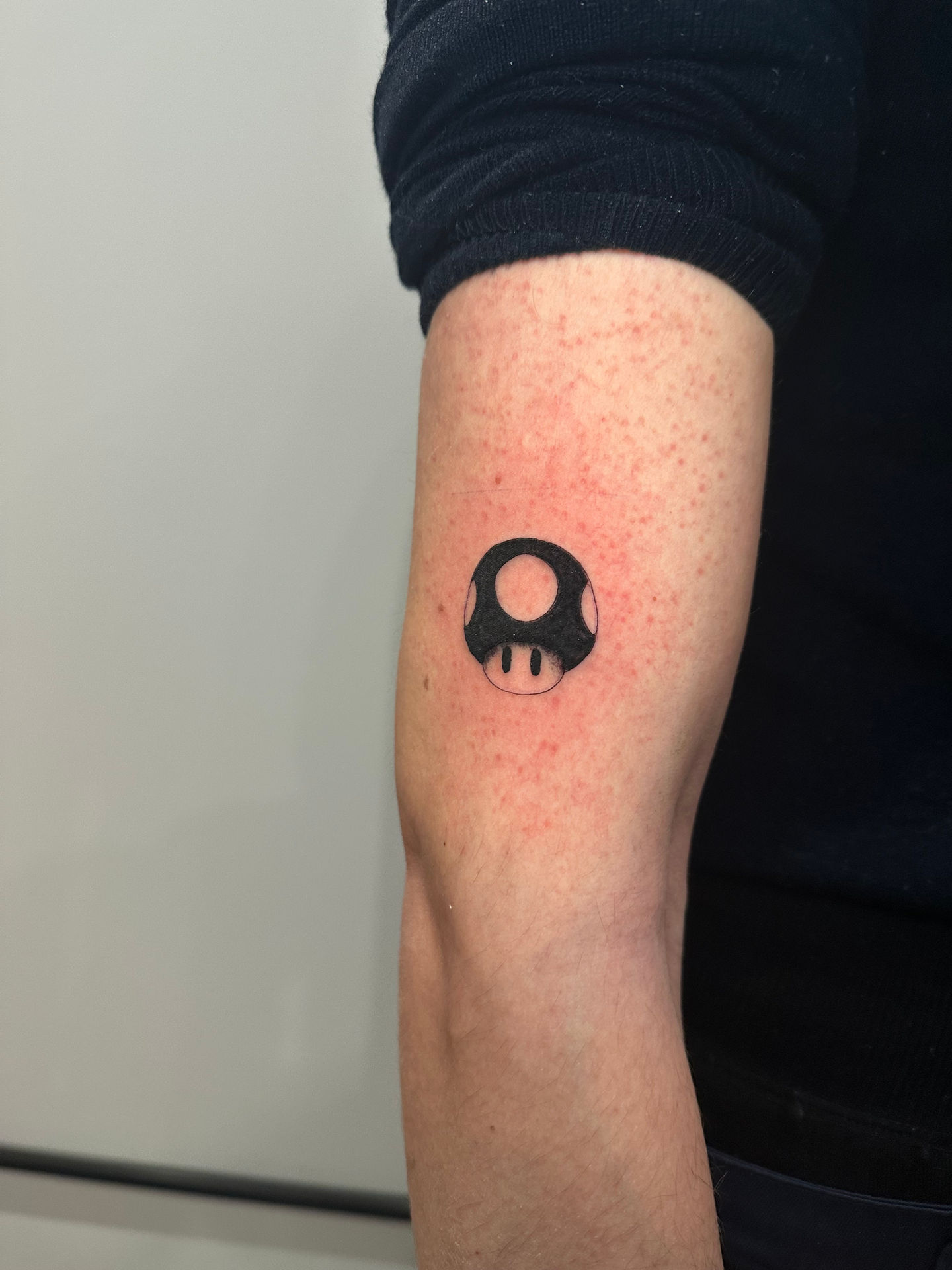 a person has a tattoo of a super Mario mushroom on their arm
