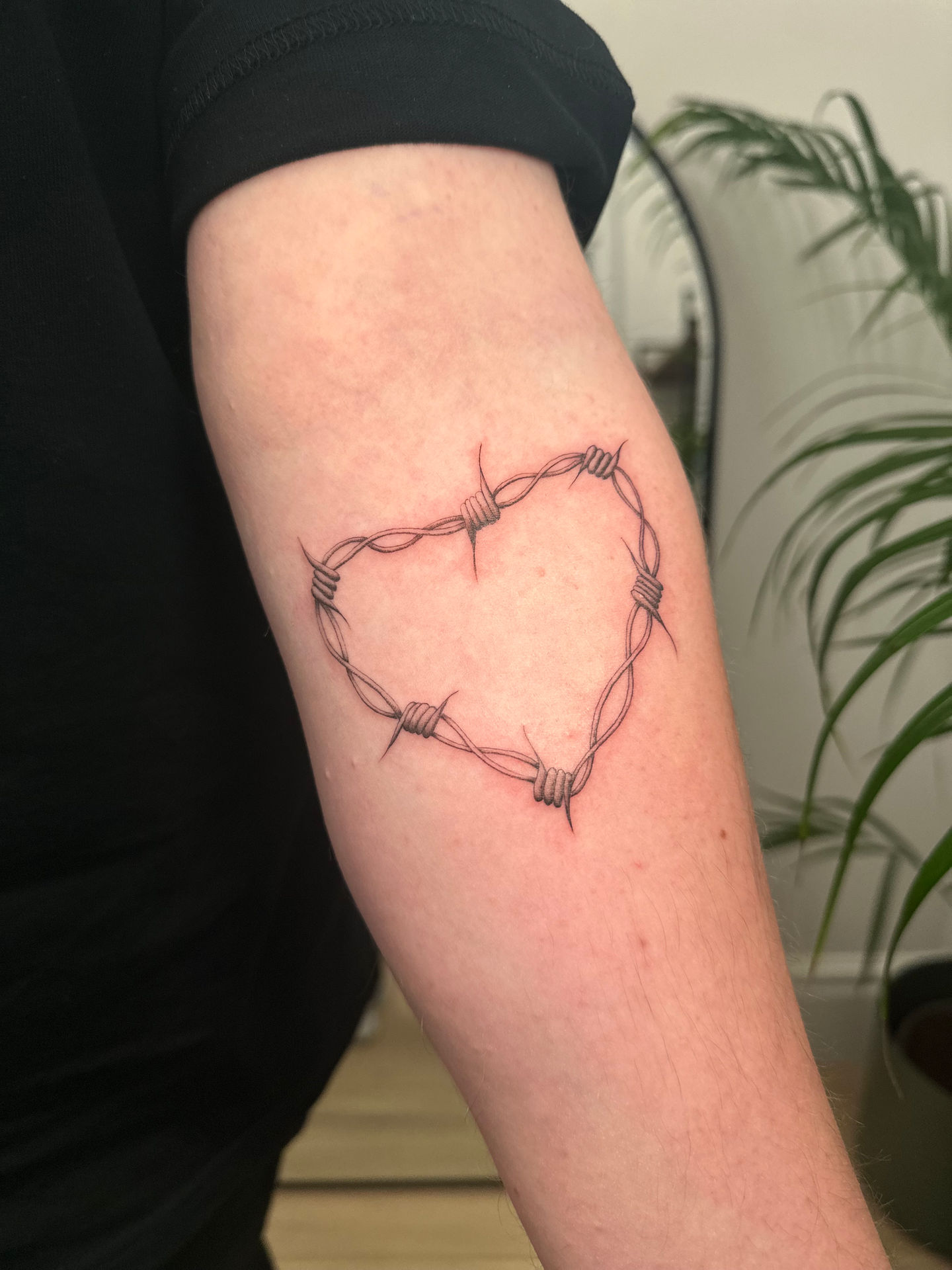 a tattoo of barbed wire in the shape of a heart