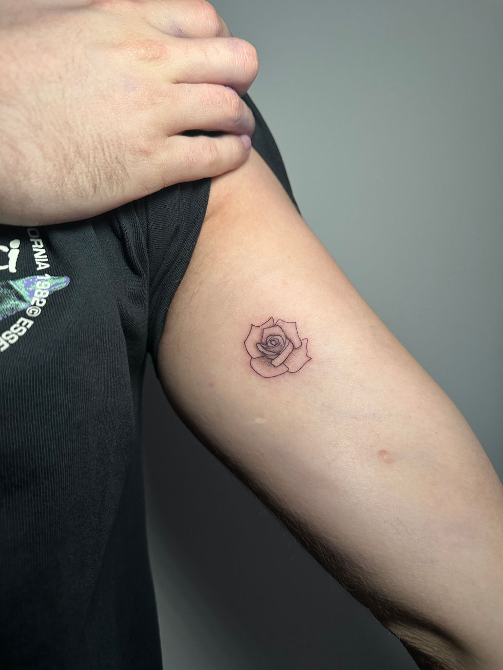 a man has a small tattoo of a rose on his arm