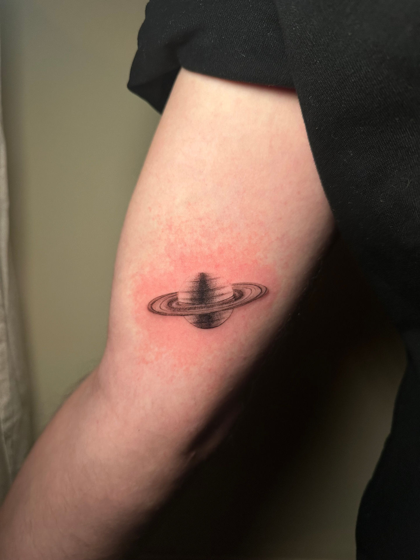 a small tattoo of the planet saturn on a person 's arm
