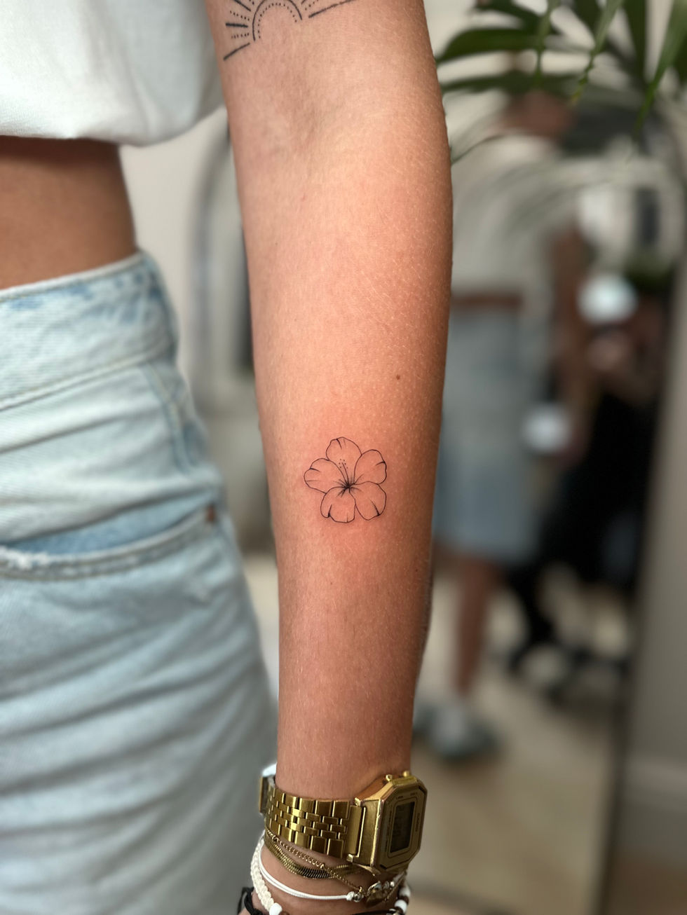 a woman has a small flower tattoo on her arm