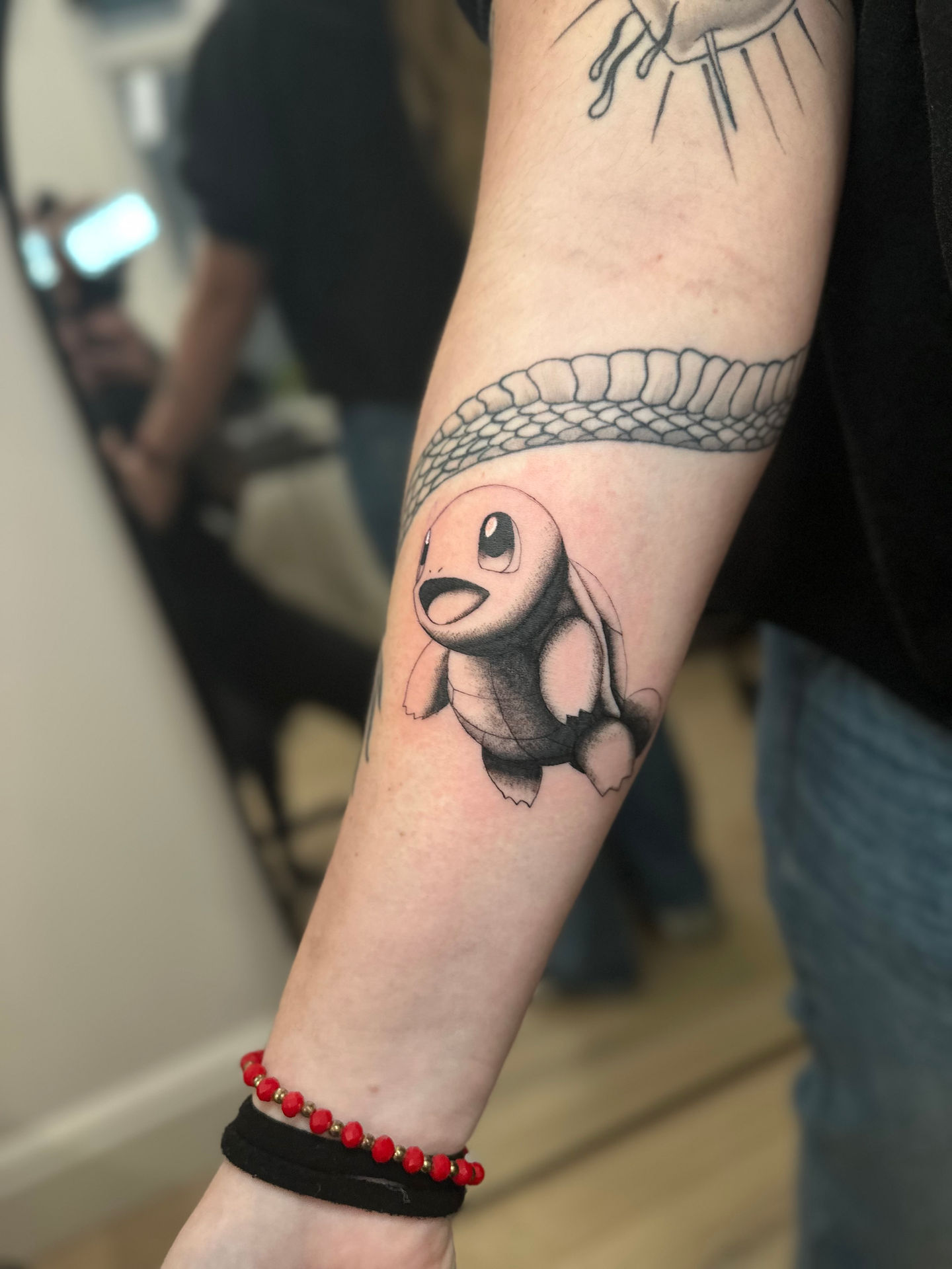 a person has a tattoo of a turtle pokemon called squirtle on their arm