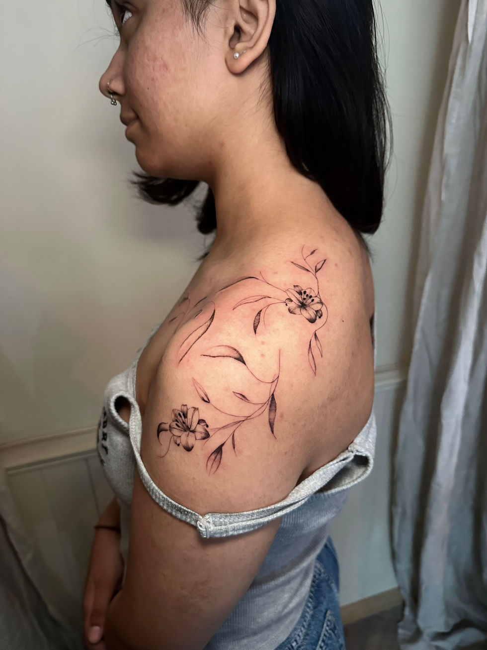a woman has a tattoo of flowers on her shoulder