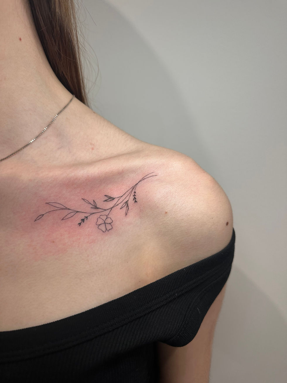 a woman has a tattoo of a flower on her shoulder