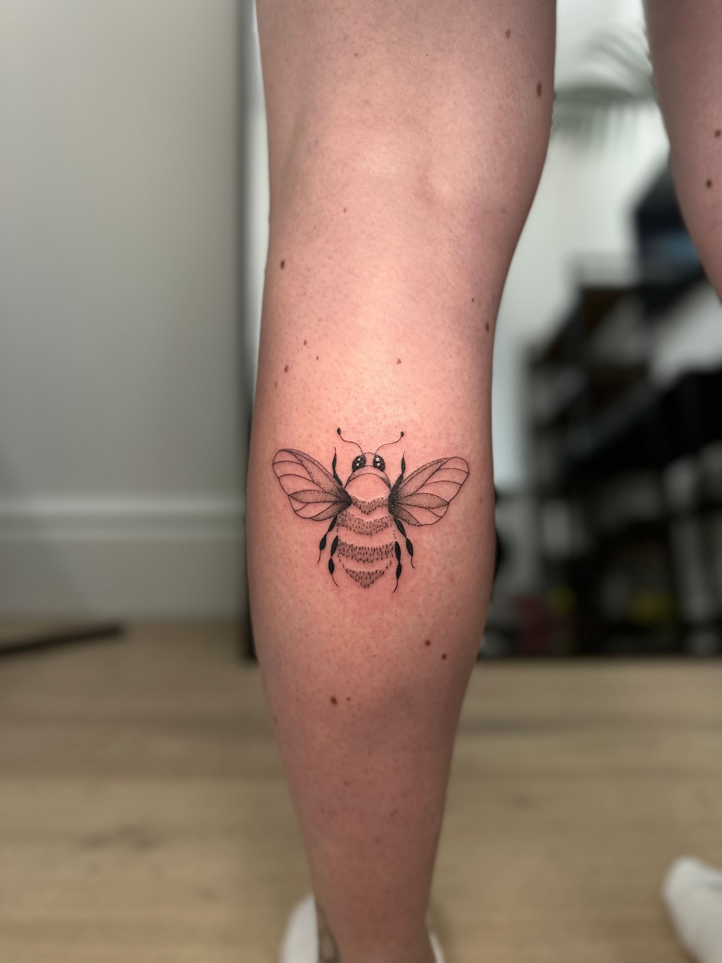 a woman has a tattoo of a bee on her leg