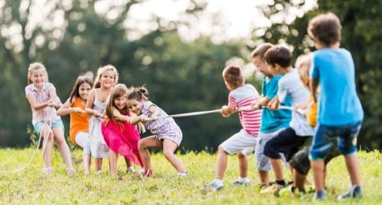 Kinder ueben Zusammenhalt beim Seilziehen