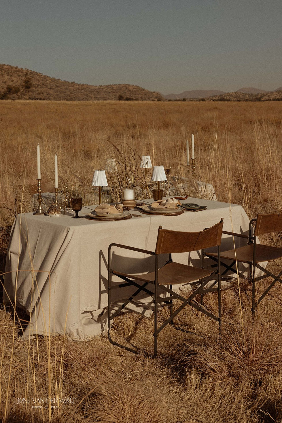 Two linen-draped reception tables set in dry Namibian grassland for an outdoor safari wedding