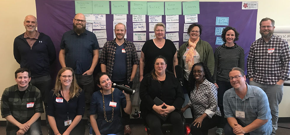 Thirteen people in front of a ToP Consensus Workshop hung on the sticky wall behind them.