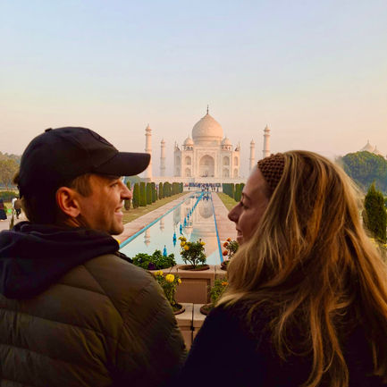 A couple looking at each other with Taj Mahal in the distance.