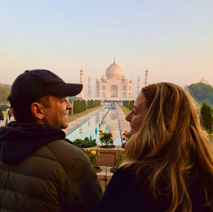 A couple looking at each other with Taj Mahal in the distance.