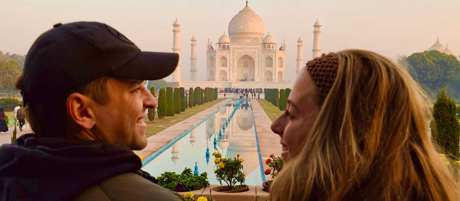 A couple looking at each other with Taj Mahal in the distance.