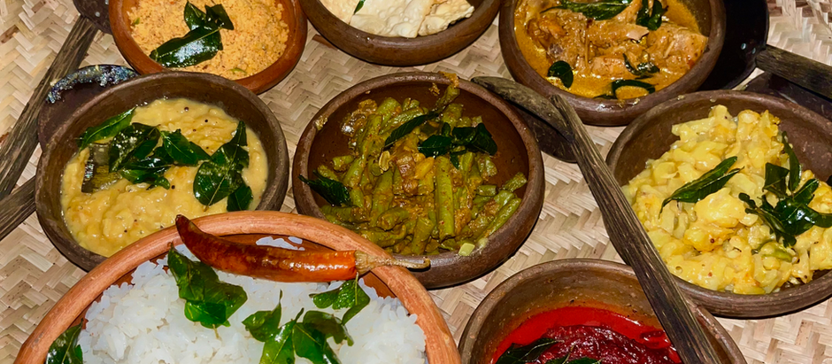 A selection of curries and rice in clay ramakins in a wooden basket.