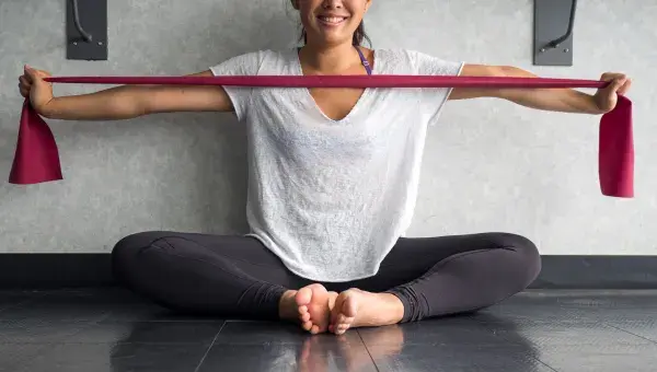 Women doing chest stretch with a band. Discover how chiropractic maintenance care and Thomas Back and Body home exercise programs can promote spinal health and prevent future flare-ups.