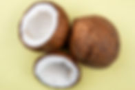 top-view-of-whole-and-halved-big-coconuts-on-yellow-surface.jpg