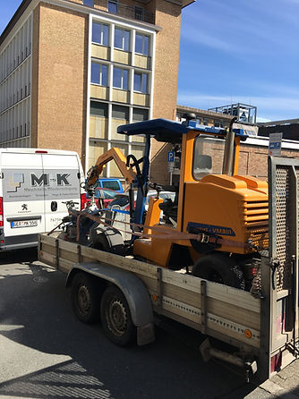 Man sieht eine Pflasterverlegemaschine auf einem Anhänger