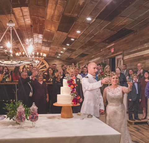 Newlyweds cutting their wedding cake inside a rustic event center at a Texas wedding venue.
