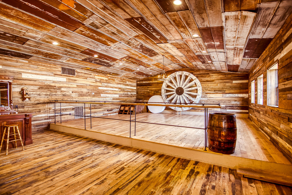 A rustic event space inside a Texas wedding venue with a wooden bar and loft seating.