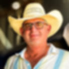 Kenn Kothman, Owner & Operations Director, smiling in a straw cowboy hat and button-down shirt, standing confidently in front of a blurred background.