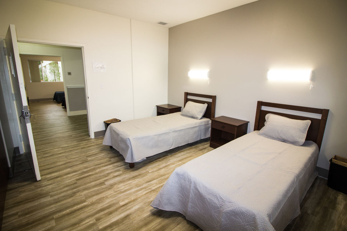 Bedroom with two beds on wood floor.