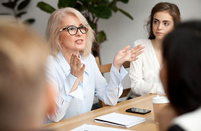 Attractive aged businesswoman, teacher or mentor coach speaking to young people, senior wo