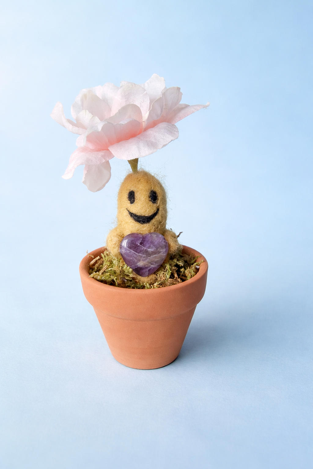 Smiling fuzzy character in pot with flower and purple heart