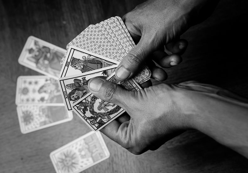 Mains étalant des cartes de tarot pendant un atelier, photographie noir et blanc