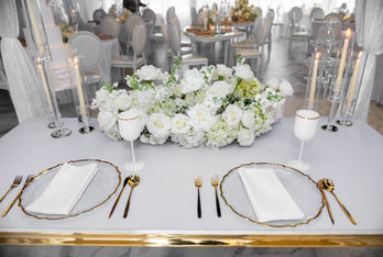 Formal table for two with white flowers and gold details.