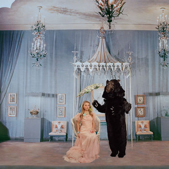 A bear holds an umbrella over a young woman although they are indoors Ruby Bowman