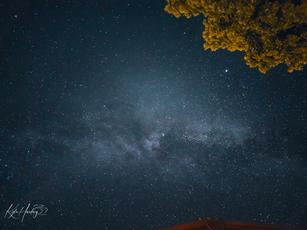a starry night sky with a lodge in the foreground