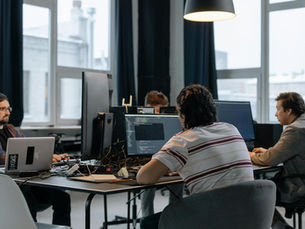 Team of developers working together on computers in a modern tech office.