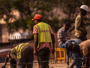 Group of male construction workers on site wearing safety gear during daytime.