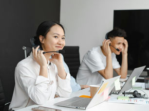 A diverse group of call center agents working with laptops and headsets in a modern office.