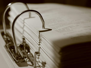Detailed sepia close-up of a binder filled with documents, emphasizing texture.