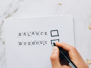 Close-up of a hand hovering over a checklist with options for balance or burnout, symbolizing stress and choice.