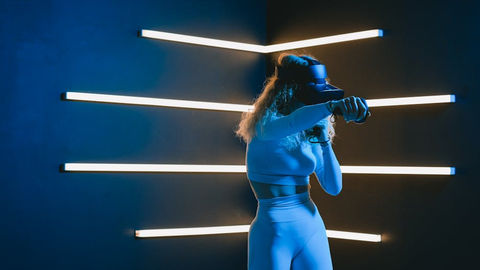 Woman with VR headset amidst modern neon lights.